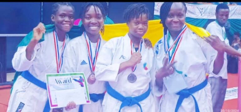 Une semaine avant la participation des équipes seniors de karaté du Bénin à l'Open de Lomé, les amazones béninoises ont marqué leur présence à Lagos lors de la 10e édition de l'Open international féminin de karaté Zainab Saleh. De retour à Cotonou lundi 21 octobre, elles ont rapporté un total impressionnant de 16 médailles , dont 6 en or, 3 en argent, et 7 en bronze. Les stars de cette compétition incluent Charmide Kolé , Joressine Kpadonou , Bararath Abé-Codjo , et leurs coéquipières, qui ont dominé le tournoi en remportant la première place au classement général. Parmi les faits marquants, la jeune Immaculé Anagonou , benjamine de l'équipe, s'est distinguée avec deux médailles d'or, tandis que Carelle Akouegnon a décroché une médaille de bronze en catégorie senior. À leur arrivée à Cotonou , la délégation, dirigée par le vice-président de la Fédération Béninoise de Karaté , René Patrick N'vèkounou , a été chaleureusement accueillie par le président Rock Armel Quenum , qui a félicité chacun des 14 athlètes pour leurs performances remarquables . Le président Quenum a souligné : « Je tiens à vous féliciter pour cette moisson. Je pense qu'on aurait pu mieux faire, mais il faut déjà reconnaître que vous avez comblé nos attentes, notamment celles du ministre des sports Benoît Dato , qui vous adresse également ses félicitations. » Les amazones béninoises ne comptent pas s'arrêter là. Elles rejoindront les seniors pour l' Open de Lomé , prévu les 26 et 27 octobre prochains, où elles espèrent poursuivre sur leur lancé de victoires. Palmarès des Béninoises à l'Open international féminin de karaté Zainab Saleh : Médailles d'or : Giovanna Aditi : 2 médailles d'or Immaculée Anagonou : 2 médailles d'or Bararath Abé-Codjo : 1 médaille d'or Charmide Kolé : 1 médaille d'or Médailles d'argent : Joressine Kpadonou : 1 médaille Marguerite Kpanou : 1 médaille Carmelia Salou : 1 médaille Médailles de bronze : Carmélia Salou Shika Garba Emmanuella Aditi Marie-Stella Odoulami Carelle Akouegnon Équipe kata Équipe kumité